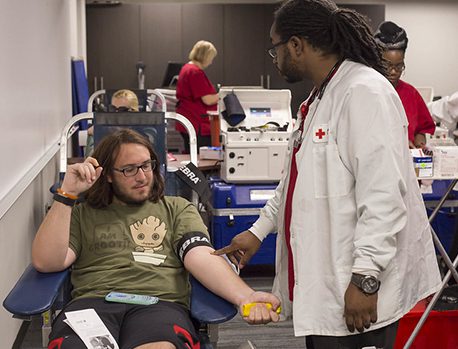 Photo from a previous blood drive of student preparing to give blood, seated in donation bed