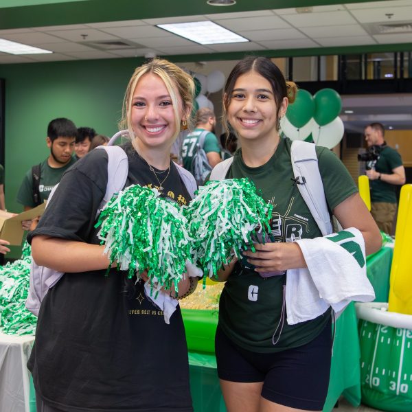 Two UNC Charlotte students holding green pom poms.